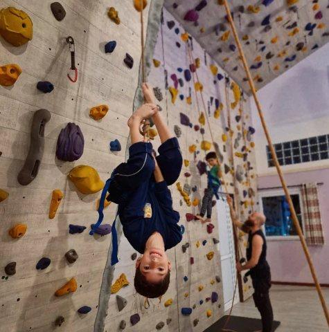 Menino de cabeça para baixo na parede de escalada