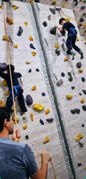 Crianças escalando a parede com instrutor